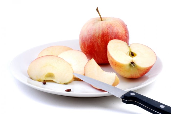 Разрезаное яблоко на белой тарелке